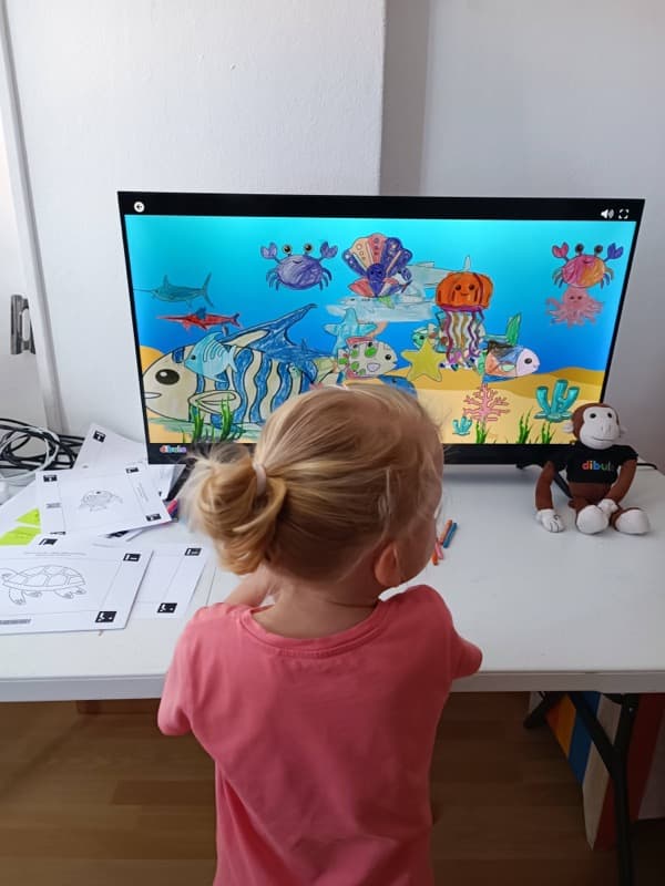 Young girl watching colored sea animals on PC screen